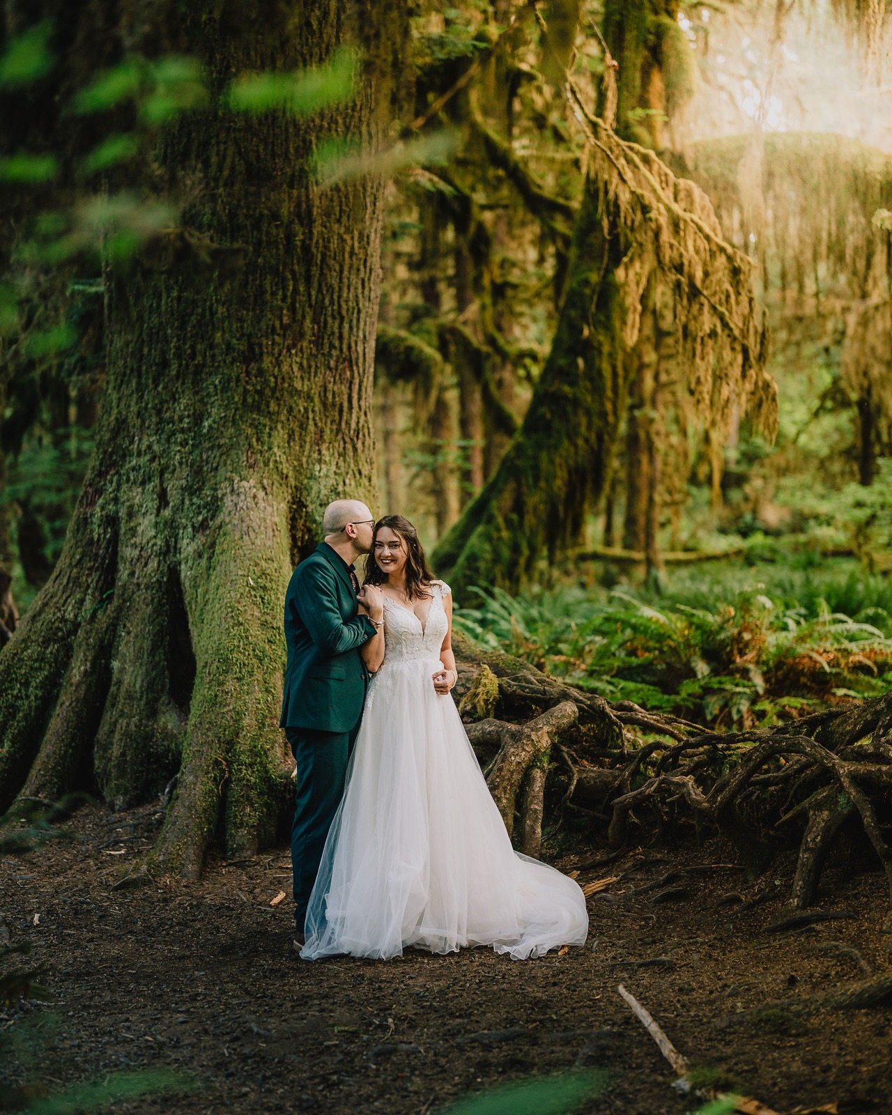 Adriana and Mitchell embracing beneath draped moss in the Hall of Mosses during their Hoh Rainforest elopement