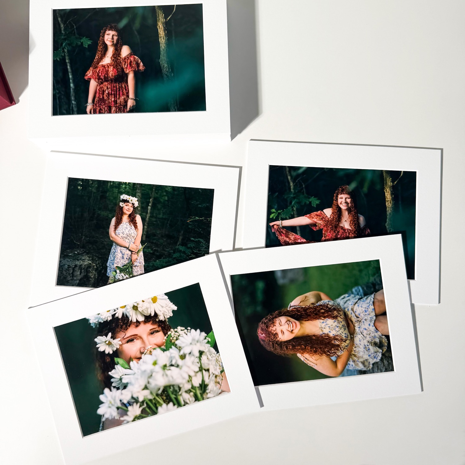 A set of matted senior portraits fanned out on a white surface