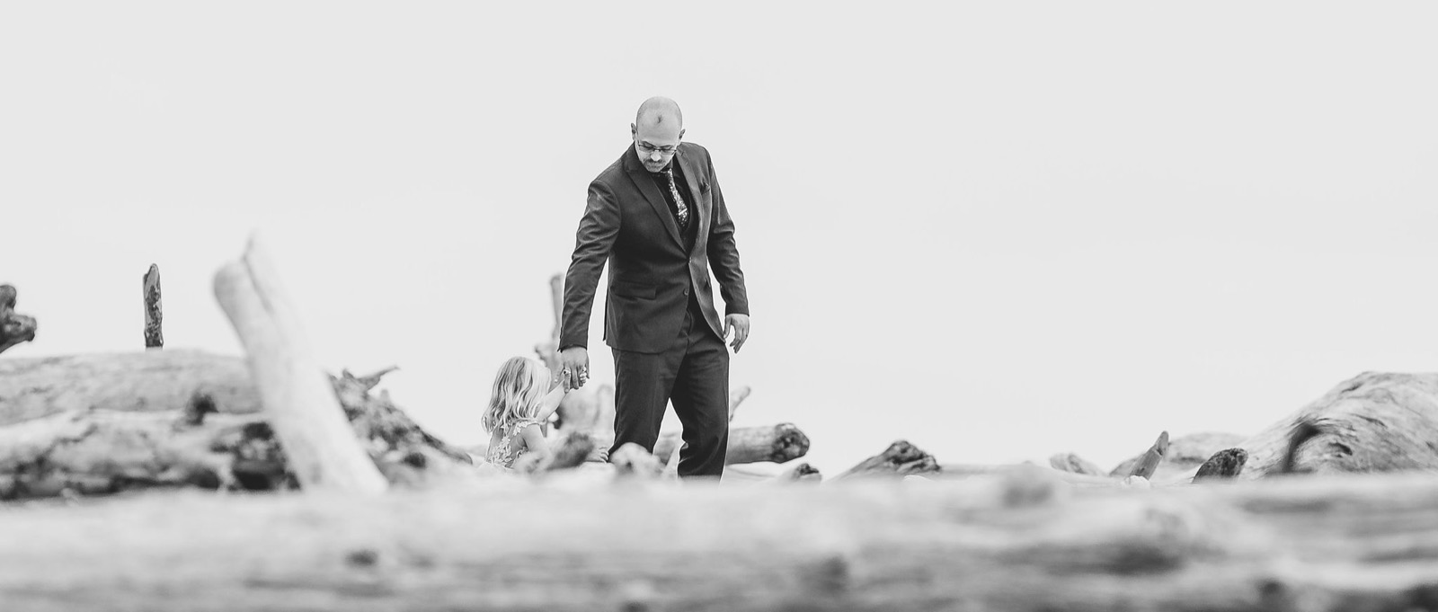 Couple tiny among driftwood and sea stacks, Washington coast, black and white
