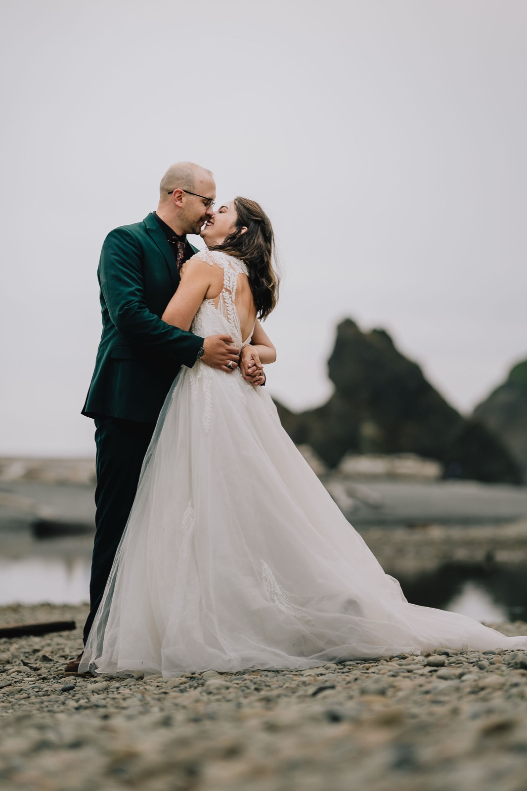 Couple kissing in the fog with sea stacks behind, Rialto Beach